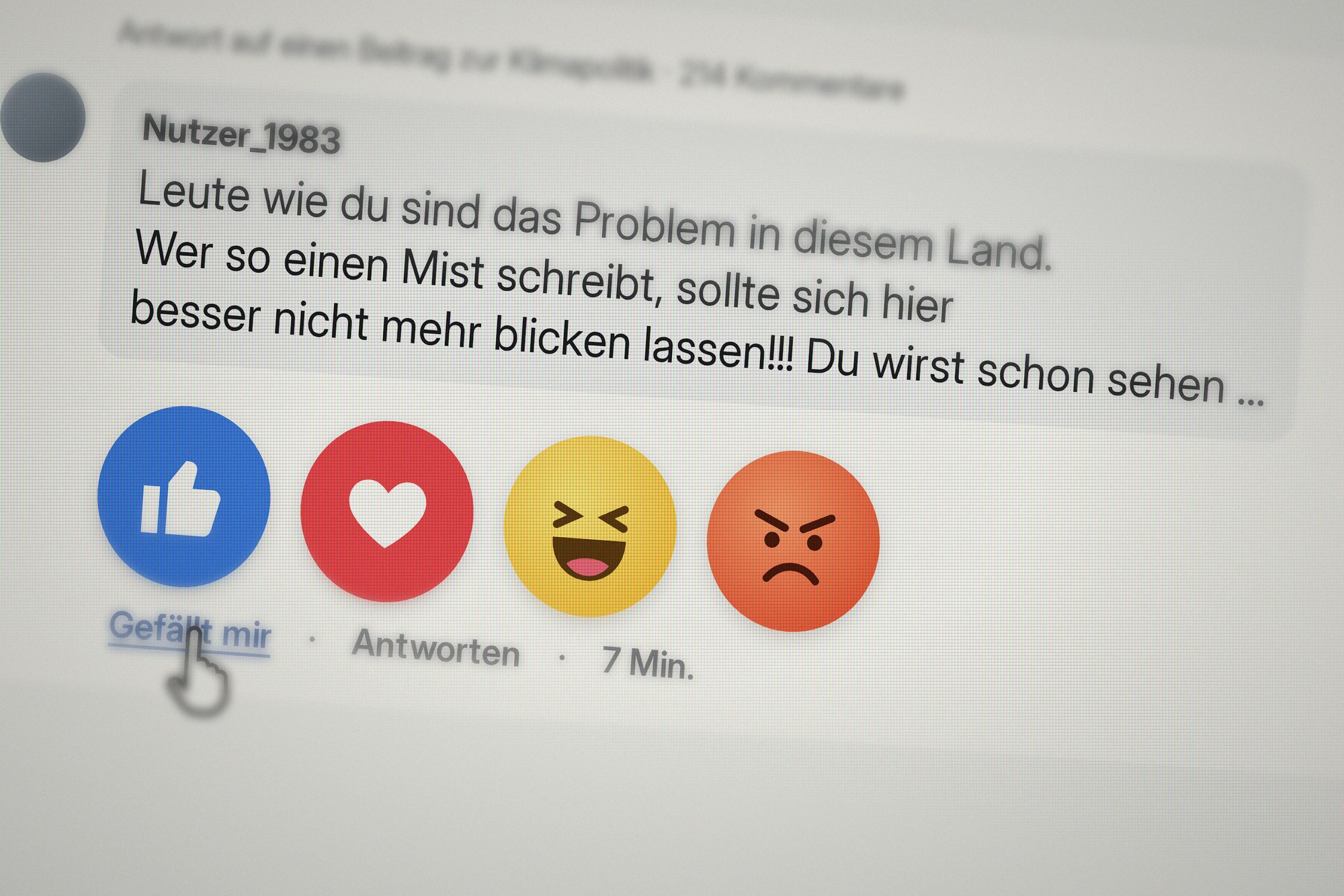 Simulierter Bildschirmausschnitt: ein Hasskommentar in sozialen Medien mit Reaktions-Buttons und dem Mauszeiger auf „Gefällt mir“